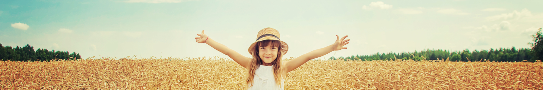 a child standing with arms outstretched, in front of tall grass